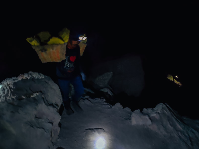 Miner climbing up the crater with sulfur rocks